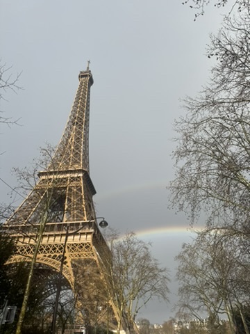 A rainbow peaks from behind the Eiffel Tower on a winter day.