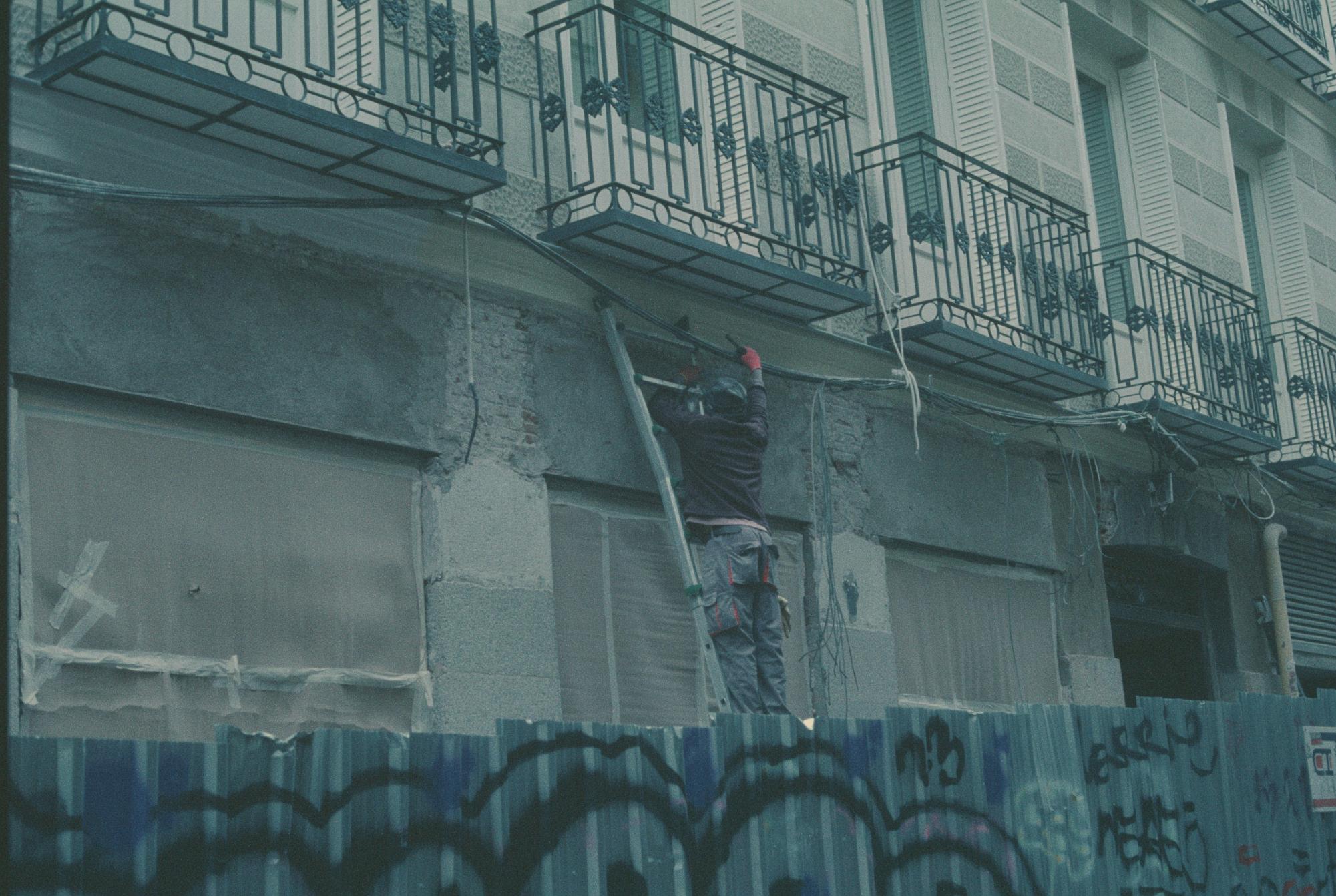 A man works amid the scaffolding of a building by the Metro de Antón Martīn, Madrid.