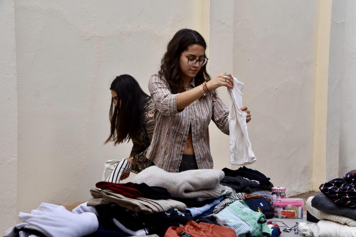 Photo of club member Kaitlyn Berry laying out clothes for the Human Rights Club thrift sale.