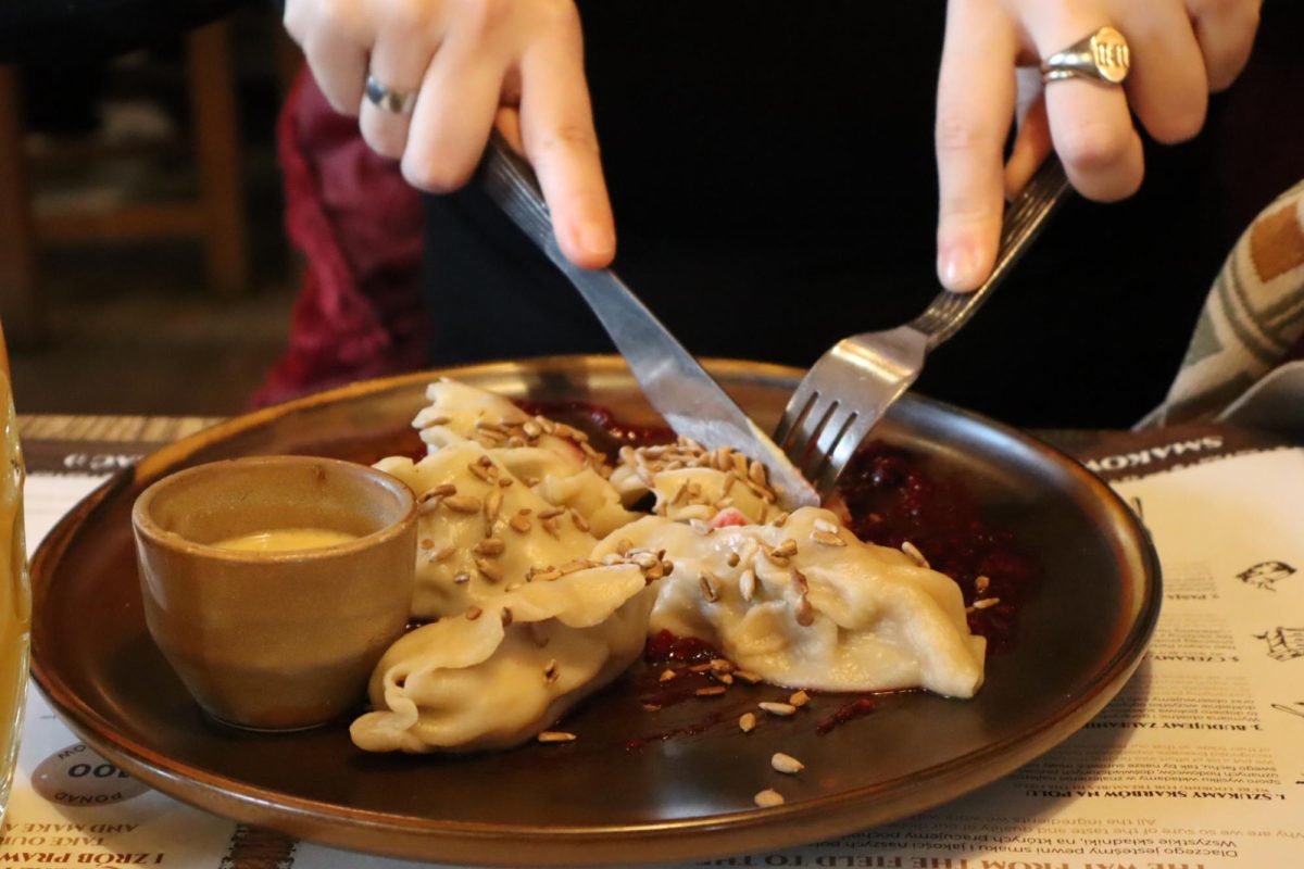 A customer eats a plate of wild boar pierogies, accompanied with honey mustard sauce.