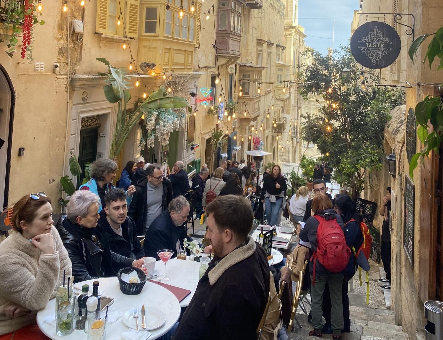 Travelers and locals eating outside of restaurants in Malta's city center.