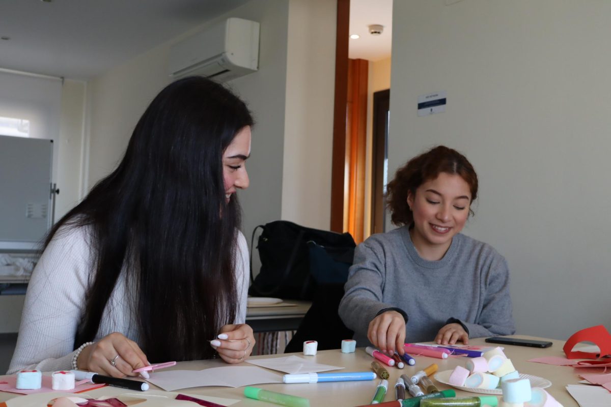 Two students at the feminist club's Valentine's Day workshop craft Valentine's themed cards.