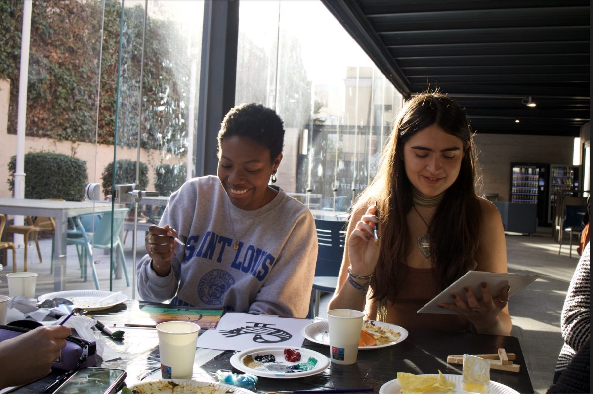 Sena Segbefia, president of BASU, and Layla Duran-Jakubec, a student in attendance, paint the Sankofa bird together.