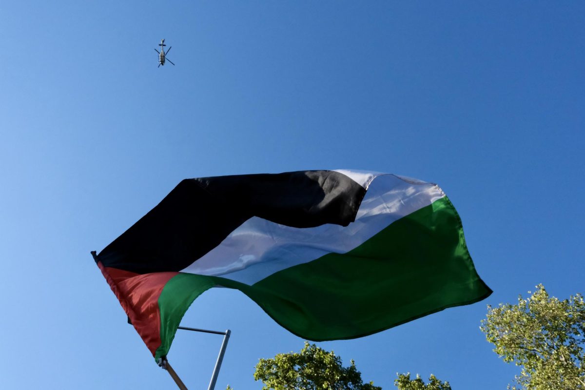 Palestinian flag flies high while a police helicopter patrols the scene