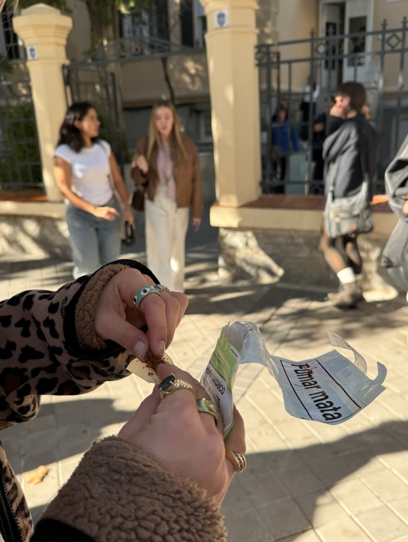 A student rolls a cigarette during a 
break outside of Padre Rubio Hall. 
