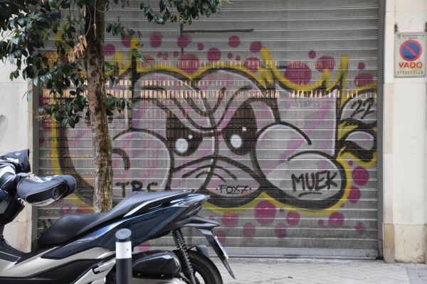 Collaborative tag of menacing eyes covering the store front of a shop in Chamberí.